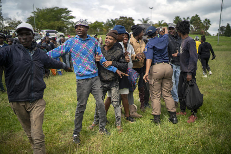 Homeless recyclers and other destitute people, some of whom said they have not eaten in three days, are asked to practice social distancing by police as they lineup in a Johannesburg park, waiting to receive food baskets from private donors, Thursday, April 9, 2020. Because of South Africa's imposed lockdown to contain the spread of COVID-19, many people who don't have savings and are unable to work are not able to buy food. (AP Photo/Jerome Delay)