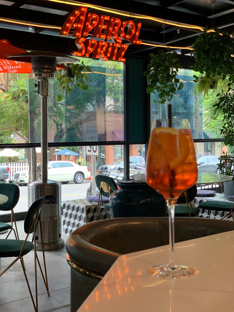 glass of aperol spritz in front of a marquee sign for aperol spritz in san diego california