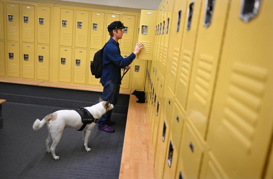 A person with a dog stands at an open locker.