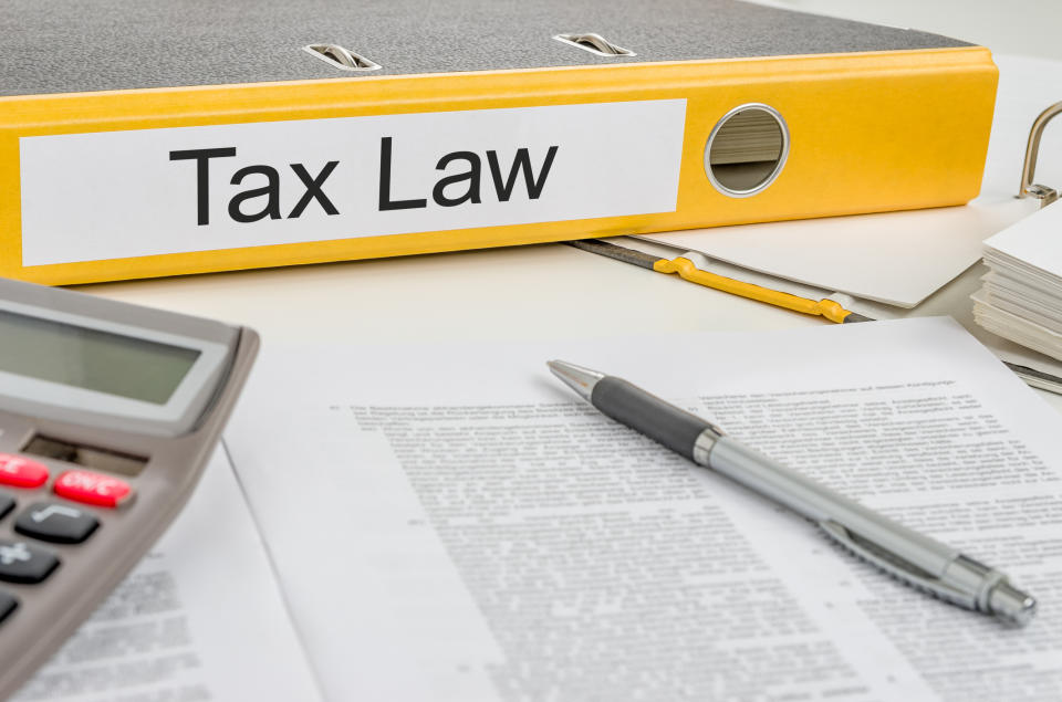 Binder labeled tax law next to documents, pen, and calculator