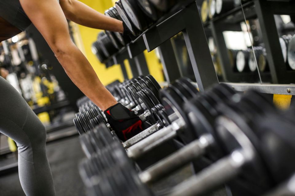 a rack of dumbbells with a close-up of a hand grabbing a weight