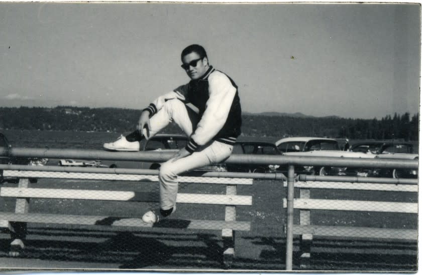 Bruce in sunglasses and varsity jacket on bleachers, Seattle, early years, looking cool as hell. Portrait.