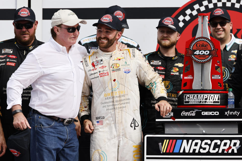 Austin Dillon receives a hug from his grandfather and car owner Richard Childress, front left, in Victory Lane after Dillon won a NASCAR Cup Series auto race at Daytona International Speedway, Sunday, Aug. 28, 2022, in Daytona Beach, Fla. (AP Photo/Terry Renna)