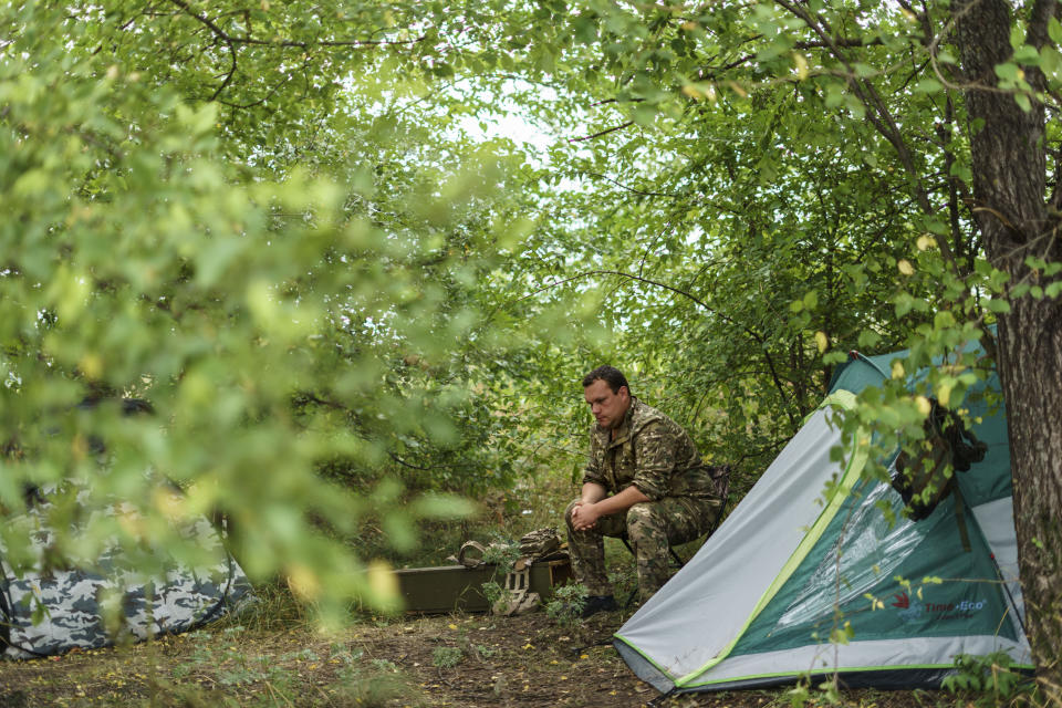 Ukrainian soldier Serhiy Artymyev with the Dnipro-1 regiment rests outside his tent during a period of relative calm around their position near Sloviansk, Donetsk region, eastern Ukraine, Friday, Aug. 5, 2022. Along with Donetsk, the neighboring Luhansk province, which has been nearly entirely controlled by Russia after Ukrainian forces withdrew in early July, makes up the industrial Donbas region which has been claimed by separatists since 2014. (AP Photo/David Goldman)