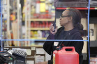 In this photo taken Wednesday, March 25, 2020, hardware store clerk Marilyn Larson works behind a plexiglass barrier built a few days earlier by a coworker to help protect employees and customers during the coronavirus outbreak, in Seattle. The store is expected to remain open under Gov. Jay Inslee's stay-at-home order issued Monday in the midst of the coronavirus outbreak, with only "essential" service providers allowed to go to their jobs. (AP Photo/Elaine Thompson)