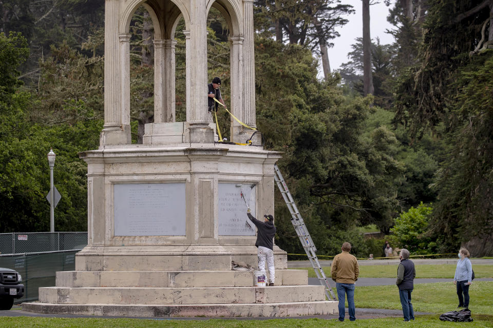 Workers from the Recreation and Parks Department paint over graffiti after a statue of Francis Scott Key was toppled from its pedestal in Golden Gate Park in San Francisco, Saturday, June 20, 2020. (Karl Mondon/Bay Area News Group via AP)