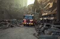 A fire truck is dwarfed by the collapsed structure as it makes its way through the debris. (Caters)