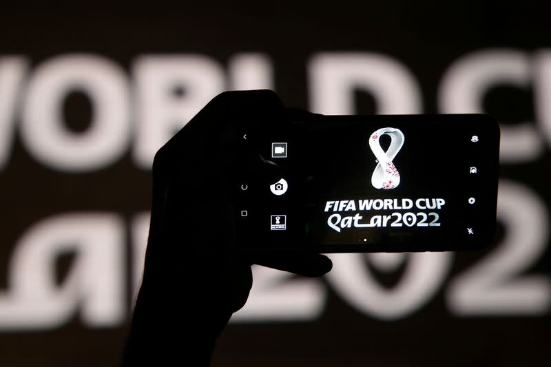 FILE PHOTO: A man takes a picture of the tournament's official logo for the 2022 Qatar World Cup as displayed on the wall of amphitheater, in Doha