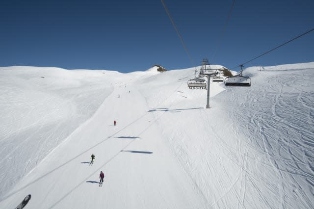 Chairlift above skiers on piste