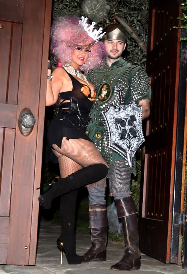 If there’s anyone who’s proven she loves a revealing ensemble, it’s Christina Aguilera, and Halloween is no exception! The 31-year-old donned a super risqué “costume” consisting of a shredded top/skirt combo, visible pumpkin-colored bra, stiletto boots, fishnets, and a pink afro wig when she hosted a bash at her L.A. home on Saturday. As for what she was dressed as, your guess is as good as ours. Boyfriend Matt Rutler went the more covered-up route as Aguilera’s knight in shining armor. (10/27/2012)