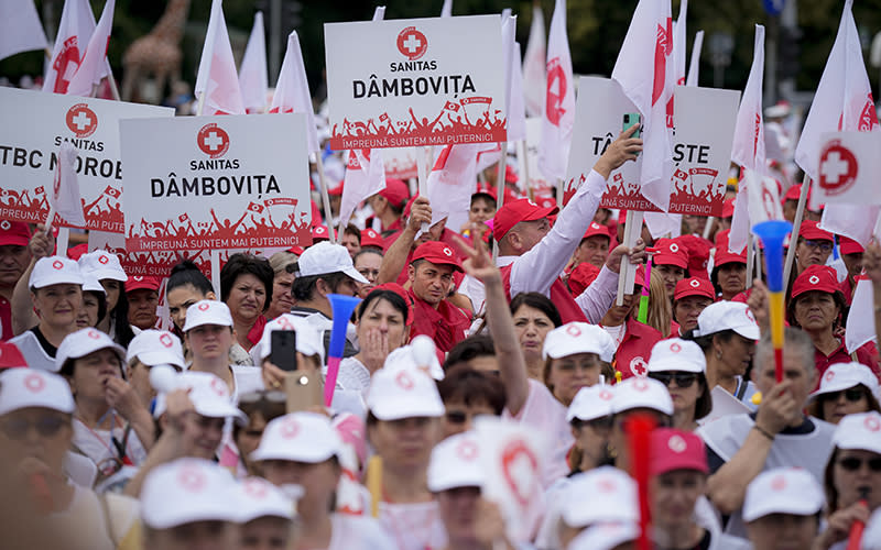 Romanian health workers with red and white hats and signs protest in Bucharest