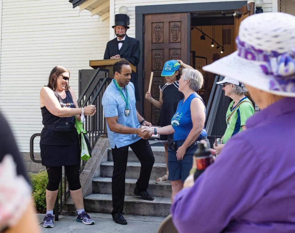 Phillip Thompson, board president and director of the Idaho Black History Museum, shakes hands with Jayne Black as she and members of Boise Galloway Training award $1,600 to the museum from a 10K Juneteenth run the group sponsored. Juneteeth was made a federal holiday this year.