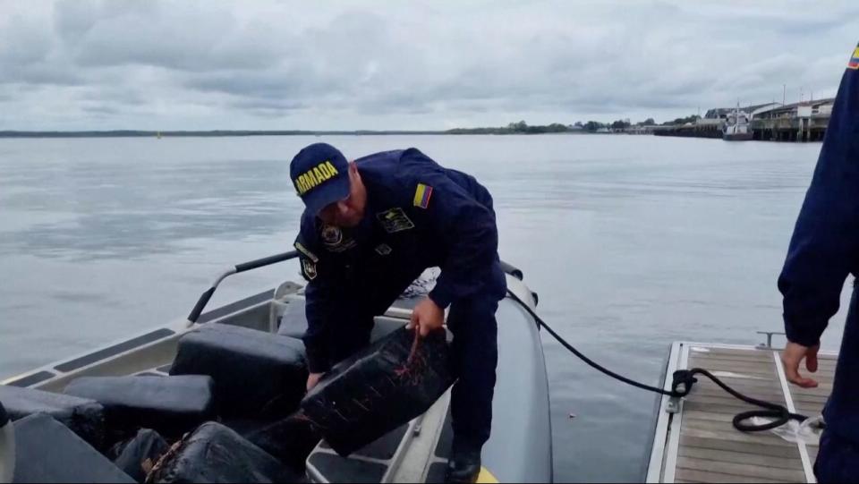 An official with the Colombian navy hands a packet of cocaine to another officer.