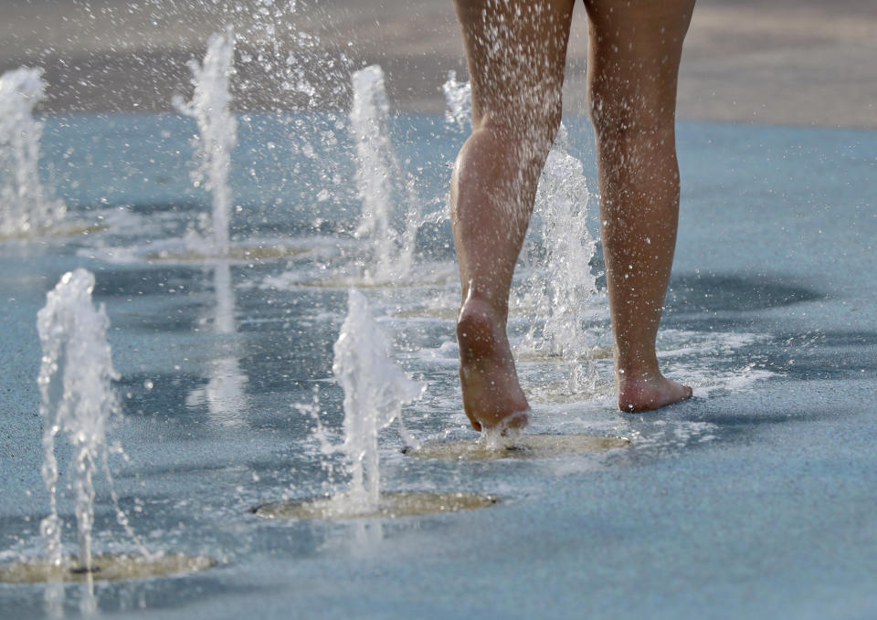 Taylor Jeremiah cools off while walking through a fountain early Monday, July 23, 2018, in downtown Phoenix. Parts of Arizona and the Southwest are bracing for the hottest weather of the year with highs this week expected to approach 120 degrees. (AP Photo/Matt York)