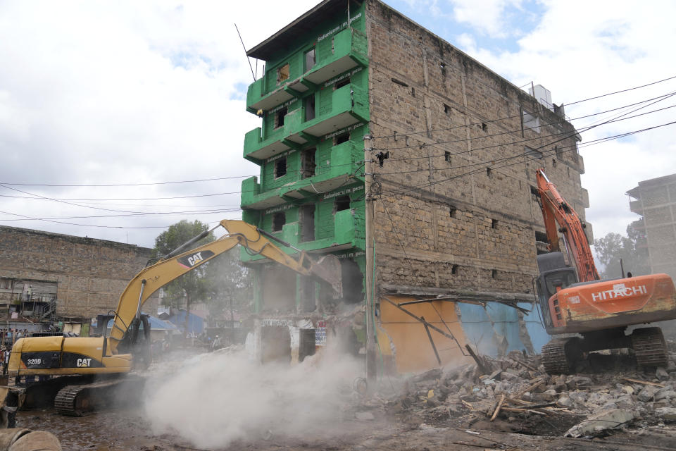 An excavator and a bulldozer bring down a building on a riparian land in the Mathare area of Nairobi, Kenya Wednesday, May. 8, 2024. The Kenyan government ordered the evacuation of people from flood-prone areas, resulting in the demolition of houses and the loss of at least one life in the melee caused by the forced evictions. (AP Photo/Brian Inganga)