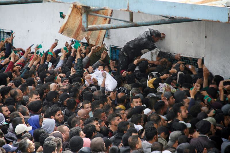 Palestinos se reúnen para recibir ayuda frente a un almacén de la UNRWA en la ciudad de Gaza