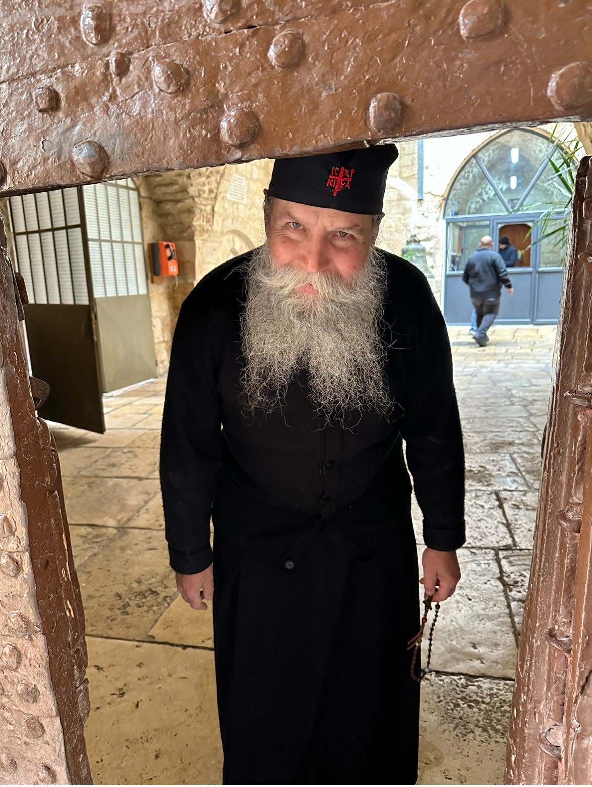 A priest looks through the opening in the Greek Orthodox patriarchate in the Old City of Jerusalem.