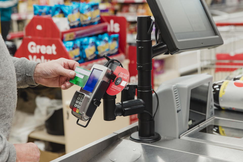 Close up shot of a senior man making a contactless payment at a supermarket till.