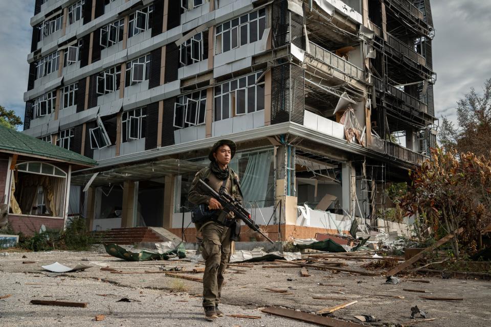 An opposition fighter patrols the streets of Loikaw 100 metres from the front line, where his comrades are battling for control of the police station. The sound of gunshots ring out, while behind him stands a hotel that was destroyed by the junta. Most of Loikaw’s 50,000 citizens headed to camps for internally displaced people in nearby forested areas before the fighting began.