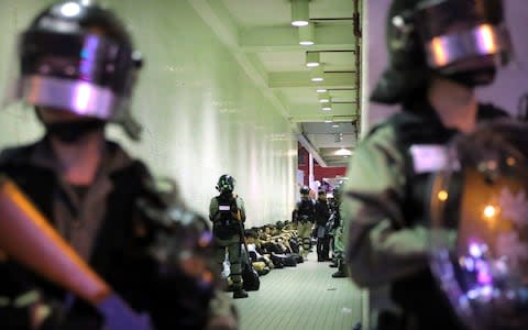 Police in riot gear stand over people detained during a protest in Hong Kong earlier this month - Credit: AP Photo/Kin Cheung, File