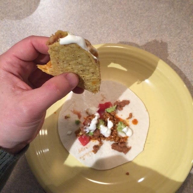 A soft taco catching ingredients from a hard taco.