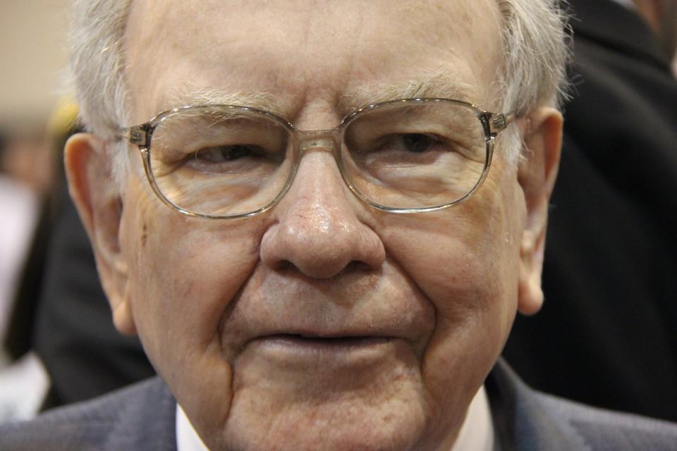 A pensive Warren Buffett surrounded by people at Berkshire Hathaway's annual meeting.