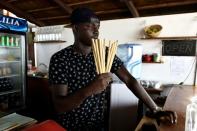 Copacabana restaurant owner Babacar Thiaw holds bamboo straws, replacing plastic straws -- a major and lasting source of marine pollution