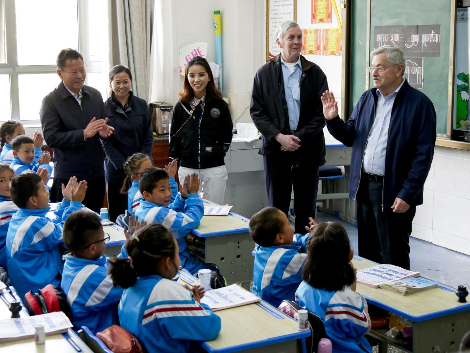 In this photo taken May 22, 2019, and released by the U.S. Embassy in Beijing, U.S. Ambassador to China Terry Branstad, right, waves to schoolchildren as he visits an elementary school in Lhasa in western China's Tibet Autonomous Region. The U.S. ambassador to China made a rare visit to Tibet this week to meet local officials and raise concerns about restrictions on Buddhist practices and the preservation of the Himalayan region's unique culture and language. (U.S. Mission to China via AP)