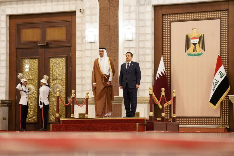 Iraqi PM Mohammed Shia al-Sudani stands with Qatar's Emir Sheikh Tamim bin Hamad al-Thani during a welcome ceremony, in Baghdad