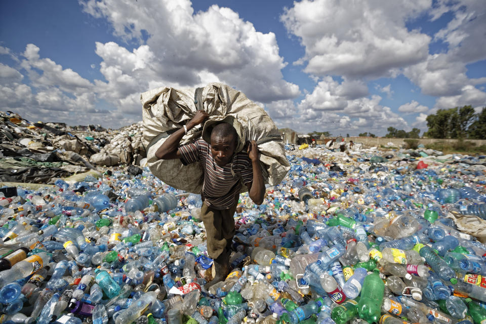 A man walks on a mountain of plastic bottles as he carries a sack of them to be sold for recycling after weighing them at the dump in the Dandora slum of Nairobi, Kenya. (Photo: AP Photo/Ben Curtis)