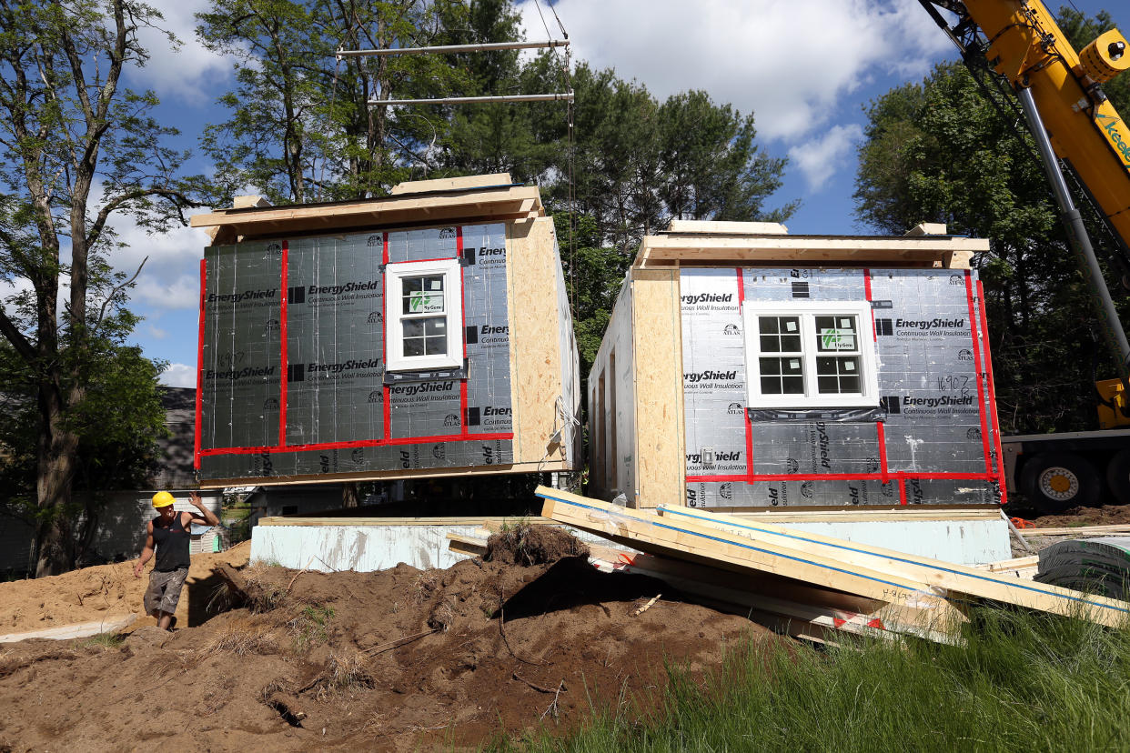 A worker from Keeley Crane Service guides the second half of an accessory dwellings unit, or ADU, to its foundation in Topsham on Thursday. The unit was built by Brunswick-based Backyard ADUs. ADUs are homes that are slightly larger than so-called tiny houses. They are becoming increasingly popular as Maine's existing housing crunch worsens. (Credit: Ben McCanna/Portland Press Herald via Getty Images)