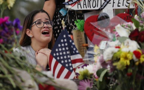 Ariana Gonzalez is over come with emotion as she visits a cross setup for her friend, football coach Aaron Feis, at the memorial in front of Marjory Stoneman Douglas High School  - Credit: Joe Raedle/Getty