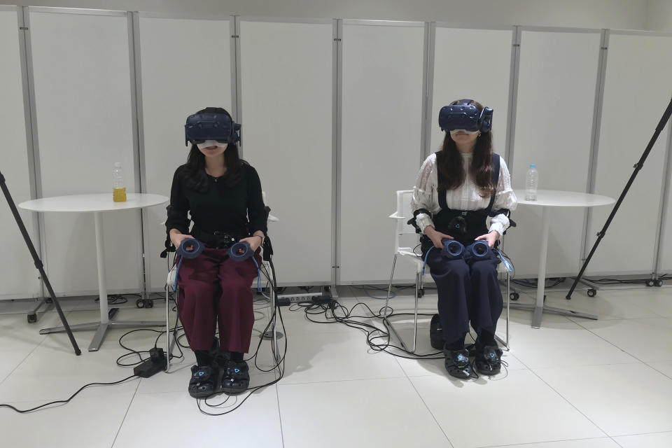 In this Oct. 18, 2019, photo, people wearing various gadgetry remote control the virtual figures that appear in a car as Nissan demonstrated such technology that is working on at its Oppama test driving course in Yokosuka, near Tokyo. The electric car with smooth four-wheel drive and a virtual friend for the coming age of automated driving are among the technology in development from Nissan. The Japanese automaker is eager to put the scandal over its former star executive Carlos Ghosn behind it. Nissan’s newly developed “all-wheel-control” technology delivers a sense of greater control and safety. (AP Photo/Yuri Kageyama)