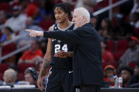 San Antonio Spurs head coach Gregg Popovich, right, talks with Devin Vassell (24) by the bench during the first half of an NBA basketball game against the Houston Rockets Sunday, Oct. 2, 2022, in Houston. (AP Photo/Michael Wyke)