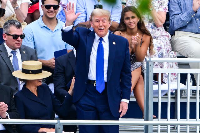 <p>GIORGIO VIERA/AFP via Getty</p> Donald Trump, standing beside Melania Trump, waves at his son Barron's high school graduation on May 17, 2024