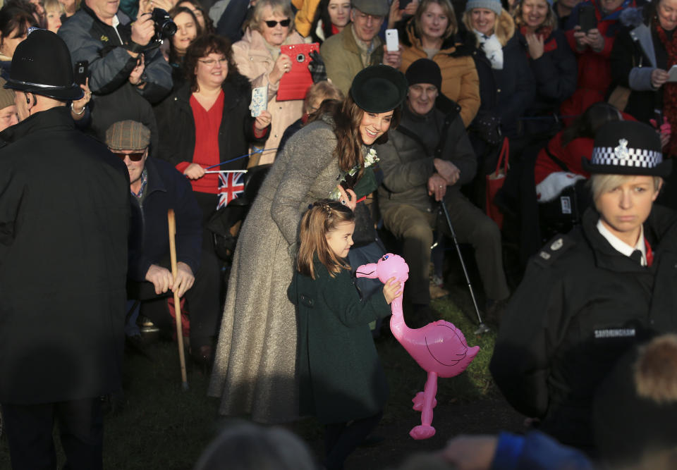 Britain's Catherine, Duchess of Cambridge, center left, speaks with her daughter Princess Charlotte as she holds a pink flamingo while greeting the public outside the St Mary Magdalene Church in Sandringham in Norfolk, England, Wednesday, Dec. 25, 2019. (AP Photo/Jon Super)