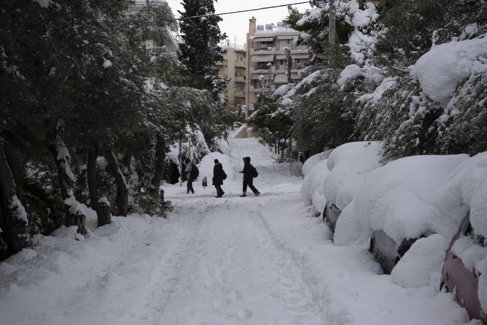 People walk in Cholargos suburb of Athens after a snowstorm, on Tuesday, Jan. 25, 2022. A snowstorm of rare severity disrupted road and air traffic Monday in the Greek capital of Athens and neighboring Turkey's largest city of Istanbul, while most of Greece, including — unusually — several Aegean islands, and much of Turkey were blanketed by snow. (AP Photo/Michael Varaklas)