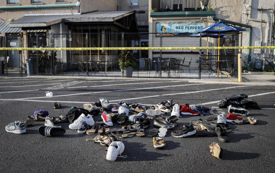 FILE - This Aug. 4, 2019 file photo shows shoes piled outside the scene of a mass shooting around Ned Peppers bar that killed multiple people in Dayton, Ohio. The FBI has labeled two of those attacks, at a Texas Walmart and California food festival, as domestic terrorism — acts meant to intimidate or coerce a civilian population and affect government policy. But the bureau hasn't gone that far with a shooting at the Ohio entertainment district. (AP Photo/John Minchillo, File)