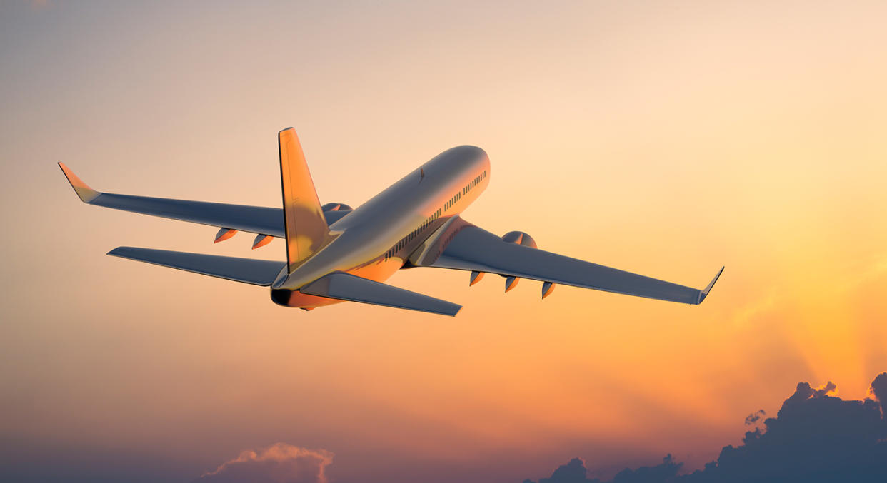 A plane flies through a dusky sky. [Photo: Getty]