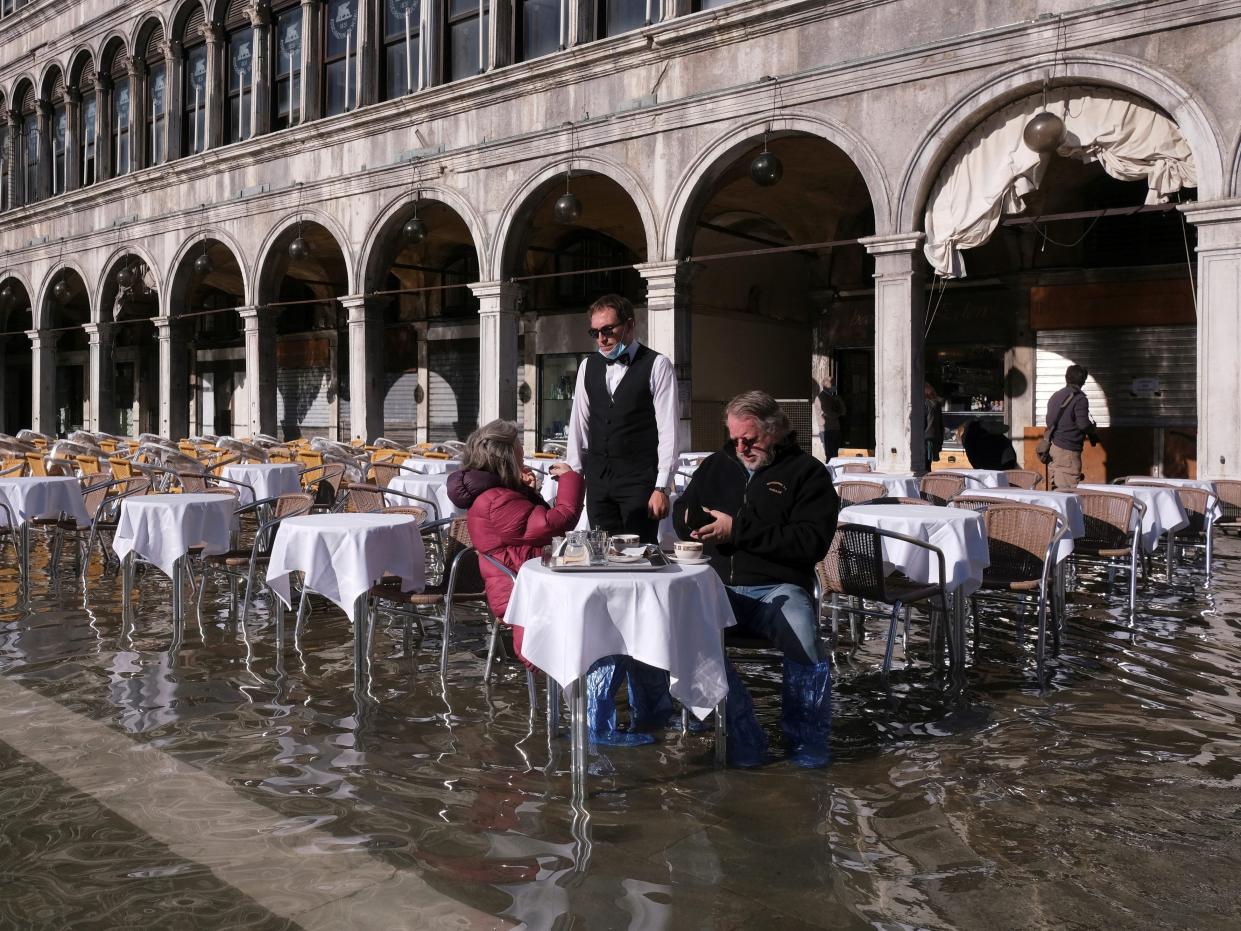 People sit at a cafe in a flooded St. Mark's Square during seasonally high water in Venice, Italy November 5, 2021.