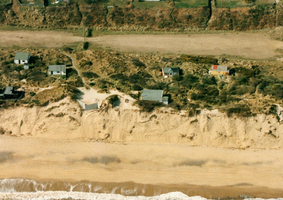 FILE PHOTO - The Hemsby shoreline in 1995. See SWNS story SWBNhemsby. Terrified residents have been evacuated from their cliff edge homes amid fears their homes could plunge into the sea during last night's storm surge. At least five people fled their homes last night in Hemsby, Norfolk, as a high tide took chunks out of the sea bank their houses sit on.  According to coastguards a new 10ft drop has formed from the high tide last night, meaning the lifeboat can no longer be safely launched out to sea. Paving slabs from residents' back gardens have fallen into the sea as several residents moved all their belongings out of their homes in the dead of night yesterday (Mar 9).