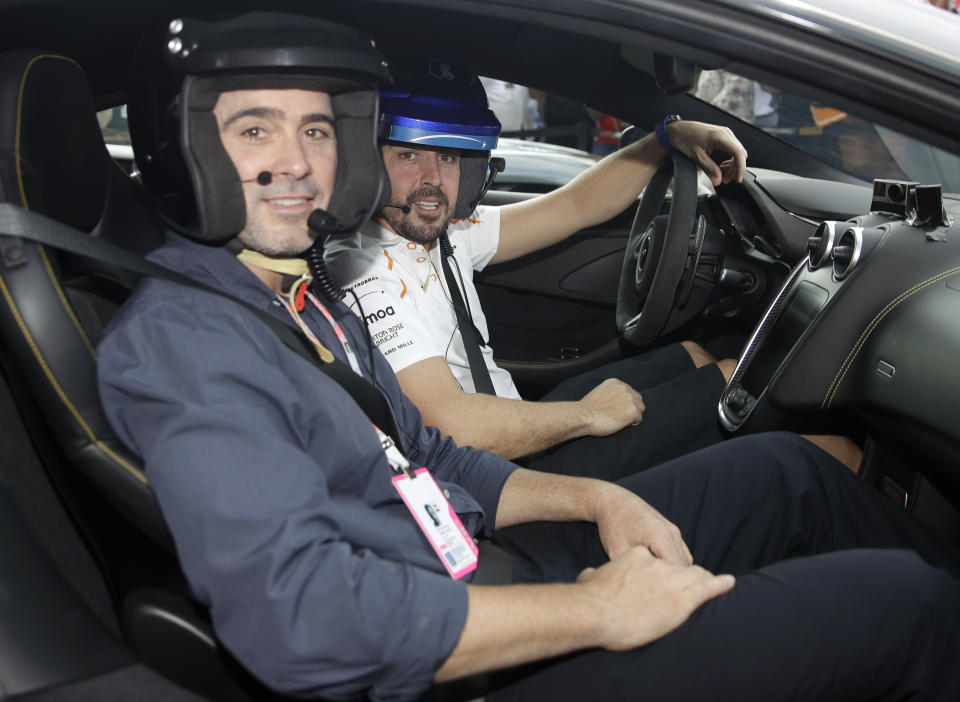 Mclaren driver Fernando Alonso of Spain, right, is flanked by Nascar World champion Jimmie Johnson before driving a McLaren 570S car at the Yas Marina racetrack in Abu Dhabi, United Arab Emirates, Saturday, Nov. 24, 2018. Seven-time NASCAR champion Jimmie Johnson and two-time Formula One champion Fernando Alonso drive Pirelli hot laps together around the Abu Dhabi F1 track on Saturday afternoon. (AP Photo/Luca Bruno)