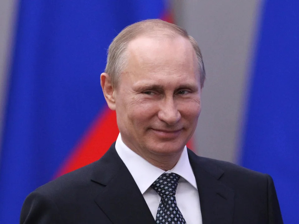 Vladimir Putin smiles.