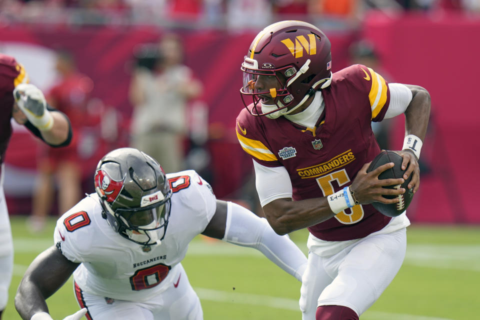 Washington Commanders quarterback Jayden Daniels, right, struggles as Tampa Bay Buccaneers linebacker Yaya Diaby (0) pressures him. (AP Photo/Chris O'Meara)