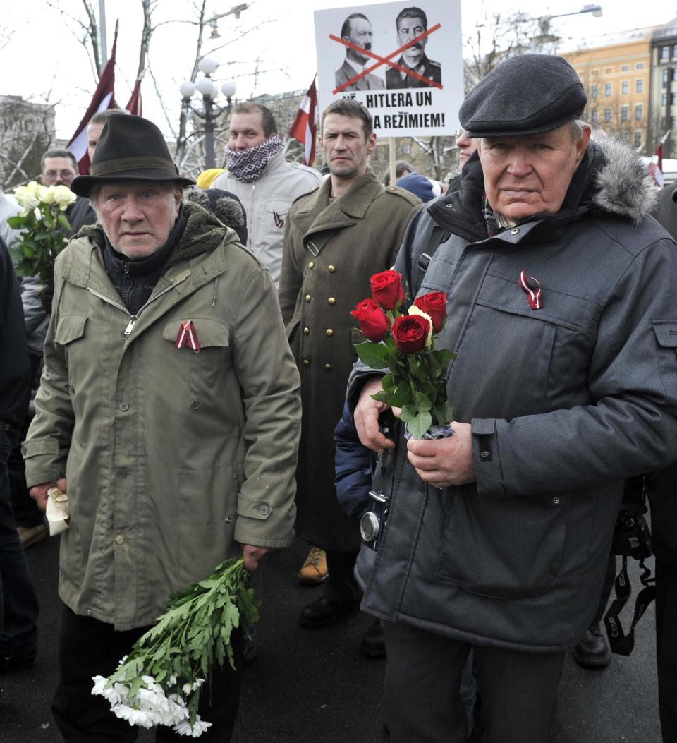 People carry flowers as they march to the Freedom Monument to commemorate World War II veterans who fought in Waffen SS divisions, in Riga, Latvia, Sunday, March 16, 2014. People participate in annual commemorations of Latvian soldiers who fought in Nazi units during WWII. (AP Photo/Roman Kosarov, F64 Photo Agency)