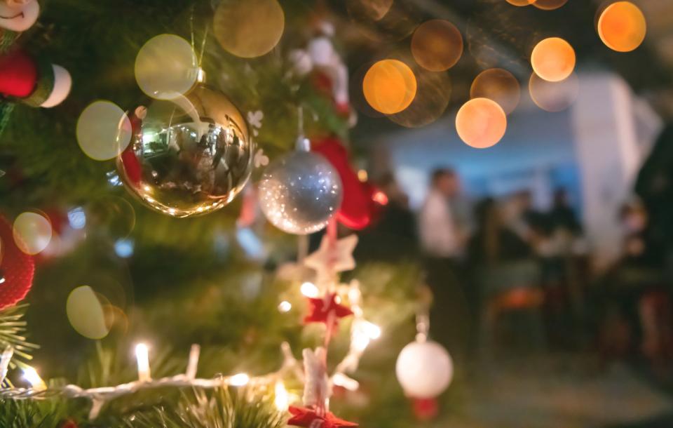 a Christmas tree with blurred, unfocused people at the office party