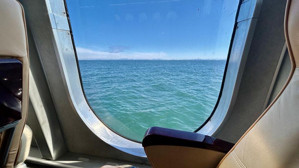 Window on ferry facing waves and blue skies