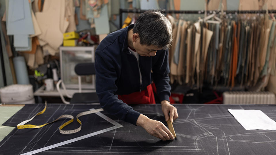 LONDON, ENGLAND - APRIL 11: Timmy Ha, originally from Vietnam and who has worked at the company for 20 years, drafts the measurements from the pattern blocks for a new piece of military dress ahead of the Kings Coronation at Kashket & Partners on April 11, 2023 in London, England. Kashket & Partners are a leading specialist for the design, development, and manufacture of uniforms for ceremonial, parade and formal wear in the UK and overseas. Their work can be seen in the scarlet tunics of the guards outside Buckingham Palace to the dress and undress uniform of the Yeomen Warders at the Tower of London. Since the beginning of the new year, work has been underway to create and roll out the new insignia, CR III, that will eventually adorn the uniforms of members of the Armed Forces, Beefeaters at the Tower of London, Police forces across the UK, British government buildings, state documents and mailboxes. Kashket has enjoyed a close relationship with royalty for many years, from the days when Alfred Kashket, the company’s founder, made felt hats for Tsar Nicholas II. The company also made the wedding uniforms of both Prince William, the Duke of Cambridge and Prince Harry, the Duke of Sussex. The company has made ceremonial wear for royalty all over the world, including eight kings, as well as the British Royal Family from whom Firmin & Sons, a sister company based in Birmingham, have the honour of a Royal Warrant, first given in 1837. Royal warrants of appointment have been issued for centuries to tradespeople who supply goods or services to a royal court. The process of changing everything from E II R, Queen Elizabeth ‘regina,’ which means queen in latin to CR III, King Charles ‘Rex,’ the latin word for king, has been years in the planning, and will take many more years to complete with around 8000 pieces of dress already changed ahead of the King's Coronation on May 6. (Photo by Dan Kitwood/Getty Images)