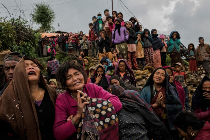 <p>Bishnu Gurung, in red, and her family and fellow villagers react as the body of her daughter, Rejina Gurung, 3, was removed from the rubble of their earthquake-destroyed home in Gumda, Nepal, on May 8, 2015. Neighbors discovered the body of the girl in the collapsed entrance of the Gurung family home, ending a 13-day search. <i>(Photograph by Daniel Berehulak for the New York Times)</i><br></p>