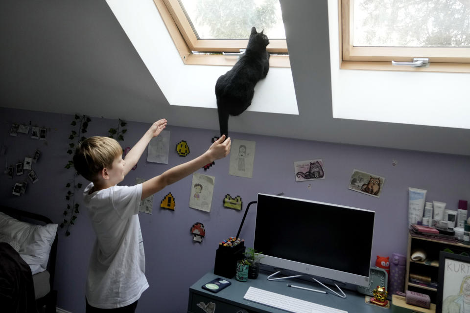 Julian Kozak, 9, plays with his cat at their home in Warsaw, Poland, Friday, April 5, 2024. Starting in April, Poland's government has ordered strict limits on the amount of homework that teachers can impose on the lower grades. (AP Photo/Czarek Sokolowski)